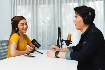 Smiling radio influencer host wearing headphone interviewing woman speaker sharing information to...