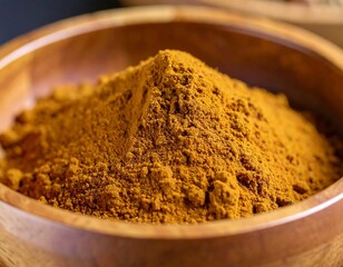 Pile of golden spice in wooden bowl