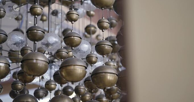 Candelabra light of metallic spheres clustered and hanging, focusing on their rustic texture and soft lighting