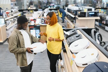 Young couple, satisfied customers buying robotic vacuum cleaner in appliances store
