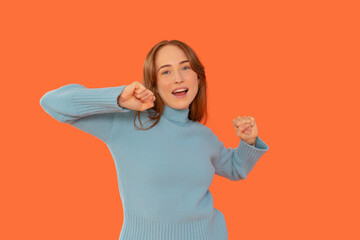 Young woman joyfully dancing in a vibrant orange backdrop, showcasing enthusiasm and positivity...