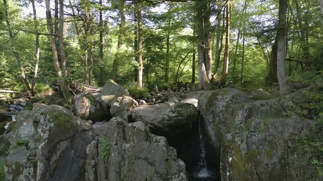 Ruisseau au milieu d'une for&ecirc;t et empilement de pierre dans les Vosges - Survol en drone