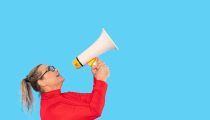Old woman in red shirt holding megaphone and communicating enthusiastically in front of a bright...