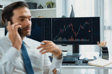 Trader businessman calling to consultant or partner with two stock exchange investment, compare...