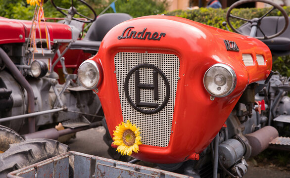 Vintage red tractor with sunflower decor on grill at outdoor display