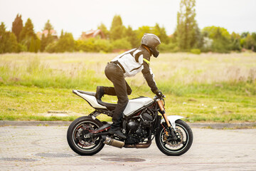 Man in a black biker suit and helmet performs extreme stunts on a motorcycle in mid-air. Dynamic...