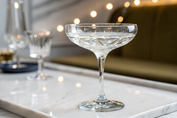 Elegant coupe glass filled with clear liquid on a marble surface perfect for cocktails and celebrations