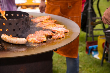 Outdoor barbecue with grilled meat sausages on a circular grill