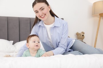Mother with her cute little baby on bed at home