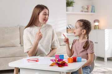 Speech therapist working with little girl indoors