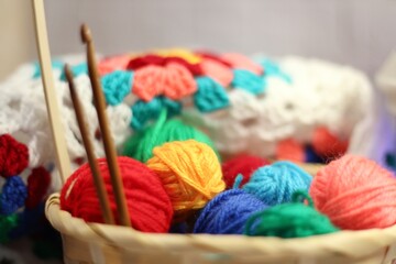 Clews balls in the basket, hooks, scissors and crocheted blanket handmade bright photo