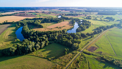 Naklejka premium Aerial View of Serpentine River Winding Through Lush Green Fields and Forests