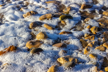 Ocean foam meets pebbled shore in a quiet meditation on presence and flow