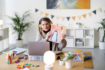 A teacher is leading a virtual class, showing flashcards to her students. She's teaching them the alphabet and animals, making learning fun and engaging from home.