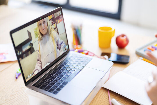 A child is video chatting with another child on a laptop. They are connecting remotely, perhaps for school or to socialize.