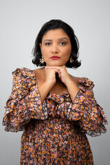 Vertical studio portrait of confident and empowered woman with chin on hands. Perfect for beauty, female empowerment, fashion and femininity. Copy space on neutral gray background.