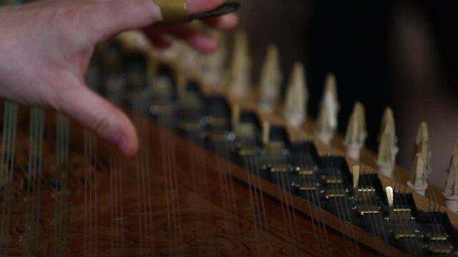 Close-up of a musician's hands playing a traditional string instrument, likely a kanoon. The intricate captures the essence of classic Middle Eastern music during a cultural performance.
