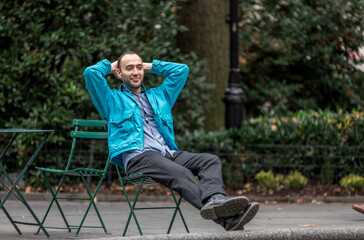Obraz premium Hispanic Man Relaxing Outdoors on Green Chair in a Manhattan Park, NYC, USA