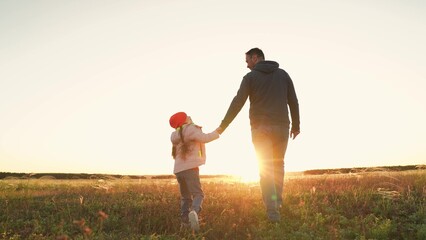 Happy family Girl daughter. Leads hand with dad through park sunset. Little girl child. eyes and...