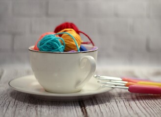  A cup and a saucer with clews balls of yarn wool handmade craft bright photo