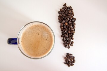 glass cup of coffee and coffee beans in the shape of an exclamation mark on a white background
