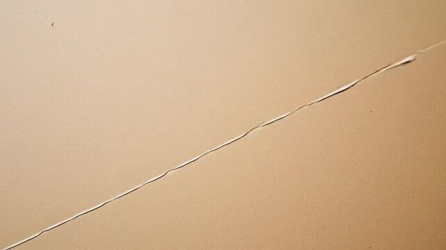 Close-up of a crack on a tan colored surface, abstract texture and design