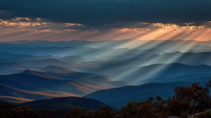 Fototapeta premium The sun shines through the clouds, illuminating the mountain range in the Blue Mountains National Park