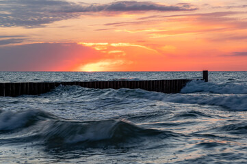 Baltic sea seascape at sunset, Poland, wooden breakwater and waves.
