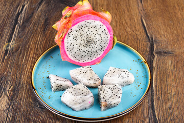 Close-up of half of pitahaya fruit and pieces of fruit pulp.
