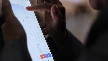Focus on close-up view of hand interacting with a mobile app displaying stock data. Captures the intensity of market analysis and digital finance. - Powered by Adobe