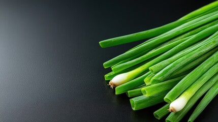Bright green onions displayed on a sleek black surface, showcasing their vibrant color and freshness, essential for adding flavor and garnish in various culinary dishes.