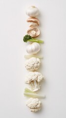 Garlic, mushrooms, broccolini, celery stalks and cauliflower arranged in vertical line on white background. Studio food monochrome color photography. Raw ingredients and healthy vegetable concept. 