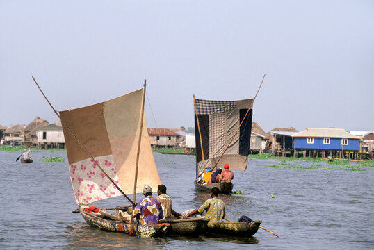 Villagers moving by sailing pirogue on Ganvie lake village in Lake Nokou, Benin