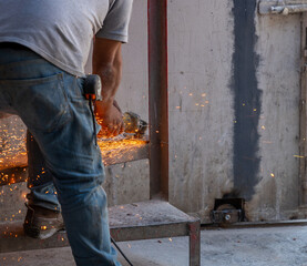 hombre cortando metal con herramienta rotatoria echando chispas