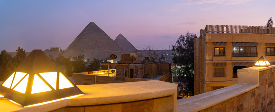 View of the Giza Pyramids from rooftop terrace at dusk, Giza, Cairo, Egypt, Africa
