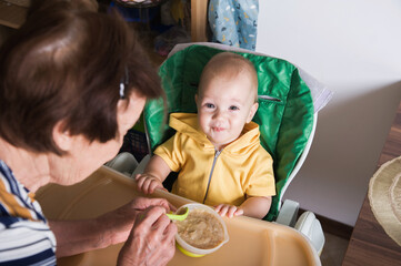 Happy Baby Being Fed by Grandmother at Home