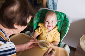 Happy Baby Being Fed by Grandmother at Home