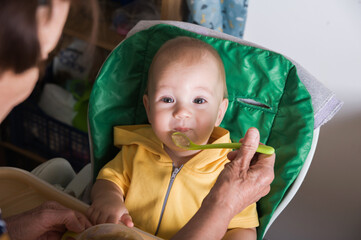 Happy Baby Being Fed by Grandmother at Home