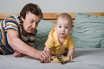 Grandmother Playing with Baby and Wooden Toy Airplane