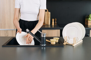 Washing dishes in a modern kitchen with a sleek black countertop setup