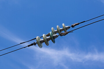 Insulators in overhead power lines against blue sky