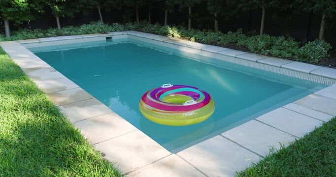 Colorful inflatable ring floating in serene backyard pool surrounded by greenery, copy space