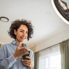 relax mature woman hold coffee and talk with public on live stream