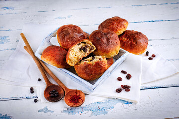 Fresh artisan baked krentenbollen - homemade sweet raisin buns offered as close-up in a wooden tray