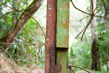Close-up detail of corroded fence in mountainous jungle.