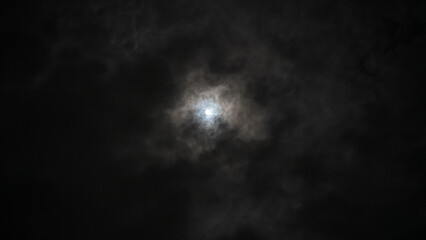 Ethereal moon obscured by swirling clouds in a dark night sky
