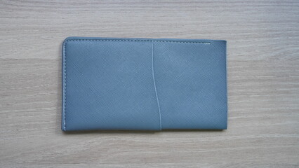 Pale Blue Passport Holder on Wood Grain Surface