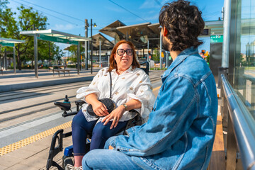Woman in wheelchair chatting with friend at tram stop