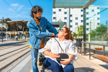 Young man assisting smiling woman in wheelchair at tram stop