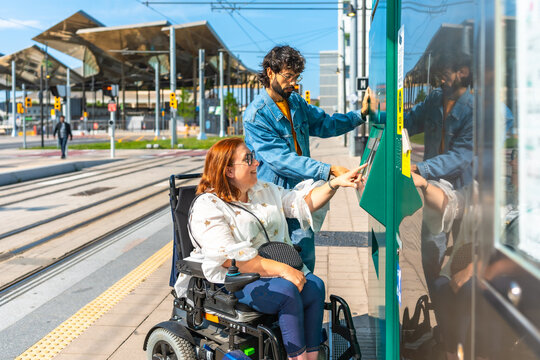Woman in wheelchair and friend buying tram ticket at station
